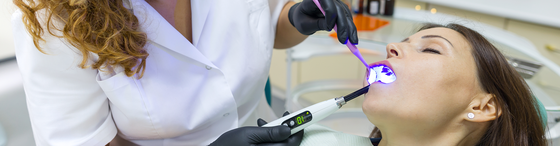 Dentist using dental tool in sleeping patient's mouth.